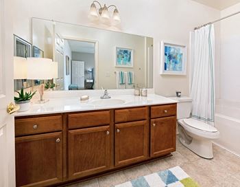 A bathroom with a white toilet next to a white sink with a mirror above it